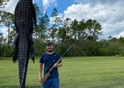 man with rifle and alligator